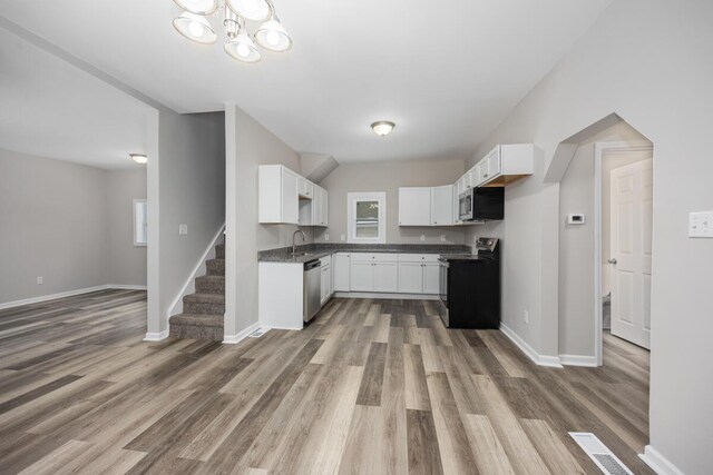 kitchen with stainless steel appliances, wood finished floors, white cabinetry, baseboards, and dark countertops