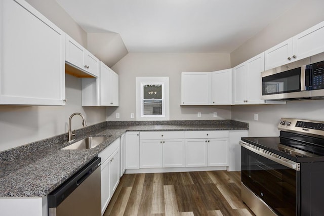 kitchen with dark wood finished floors, white cabinetry, stainless steel appliances, and a sink