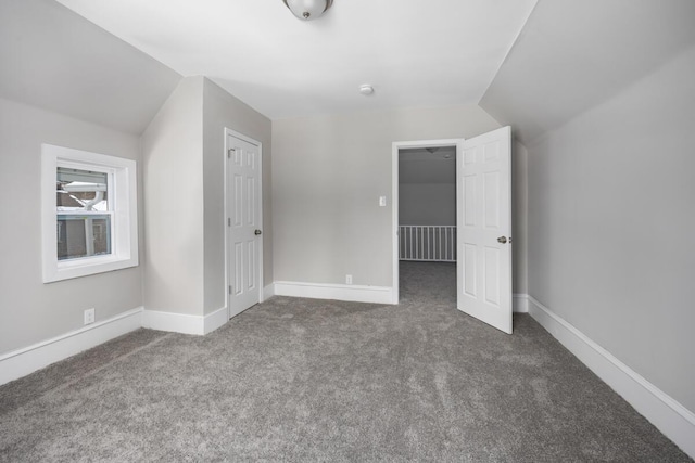 unfurnished bedroom featuring vaulted ceiling, carpet floors, and baseboards