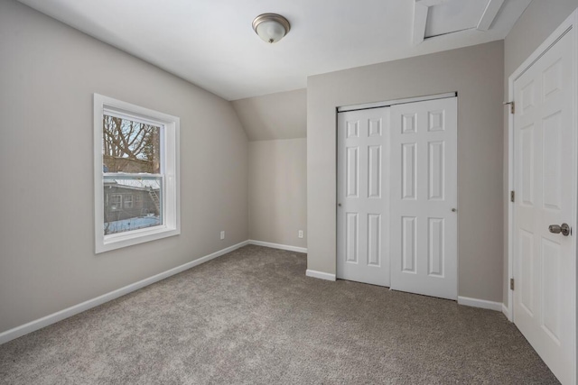 unfurnished bedroom featuring a closet, baseboards, vaulted ceiling, and carpet flooring