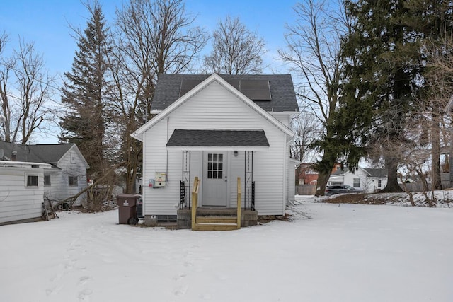 view of front of house with a shingled roof and solar panels