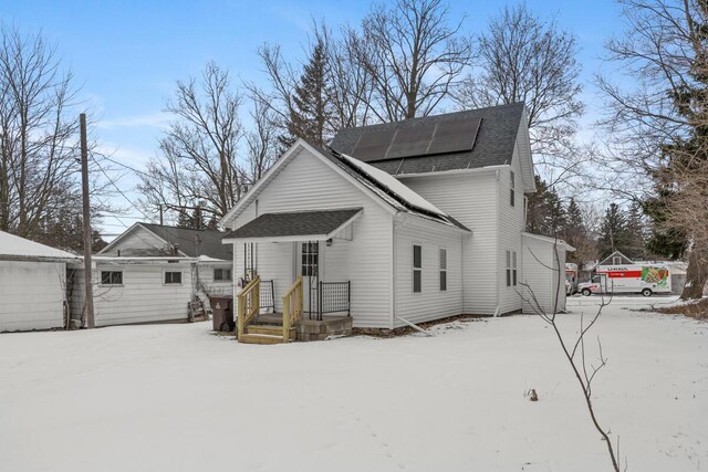 exterior space with a shingled roof and solar panels