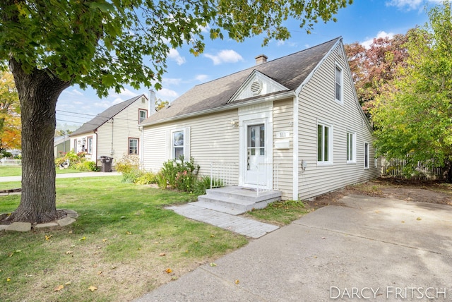 view of front of property with a front yard, roof with shingles, and a chimney