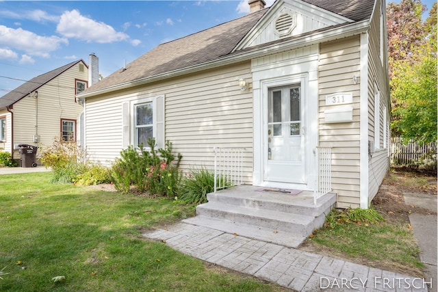 exterior space with roof with shingles, a chimney, and a front yard