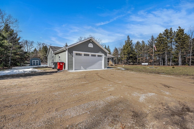 view of side of home featuring a storage unit, an outbuilding, and driveway