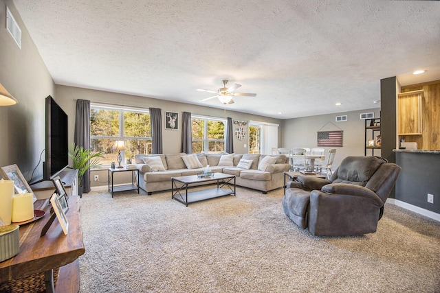 carpeted living room featuring baseboards, visible vents, and a textured ceiling