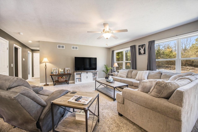 living room featuring a ceiling fan, light colored carpet, visible vents, and baseboards