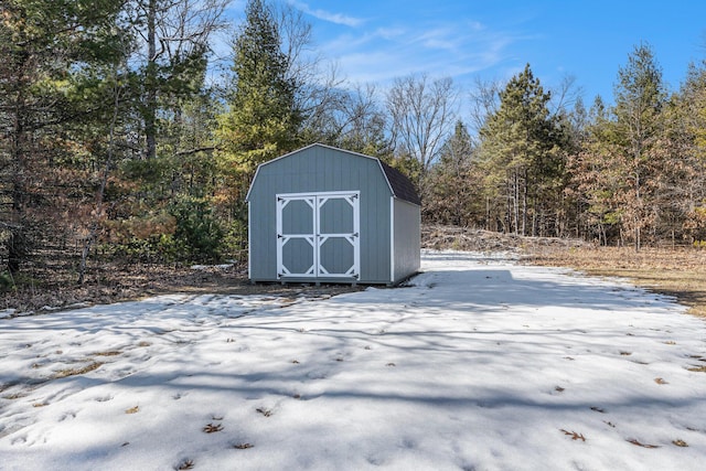 snow covered structure featuring a storage shed and an outbuilding