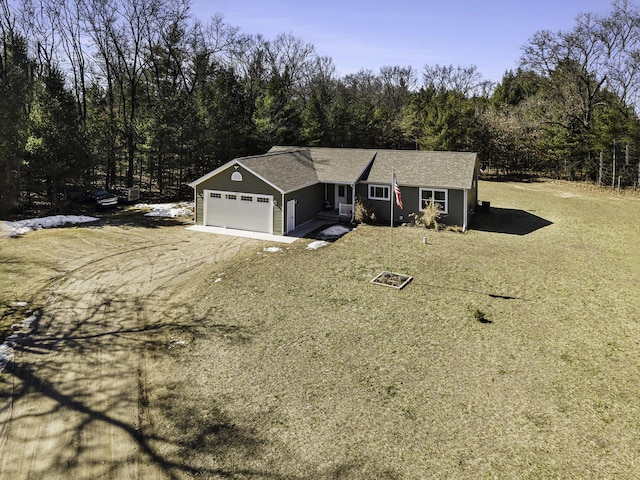 single story home with an attached garage, a forest view, and dirt driveway