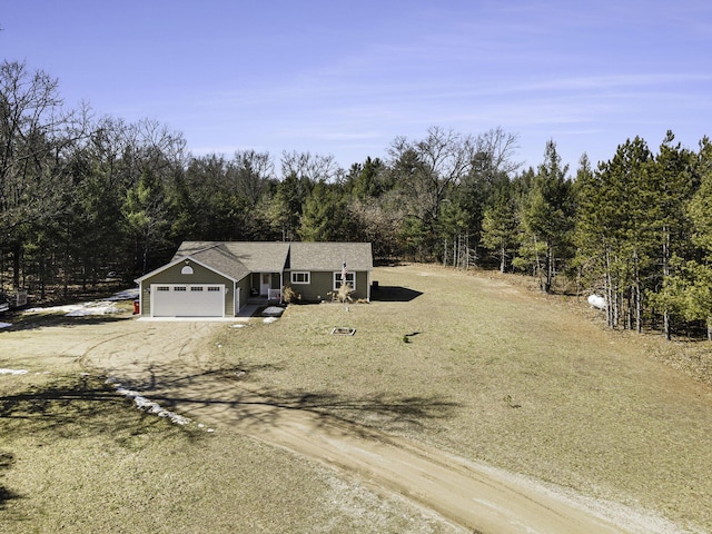 view of front facade featuring a forest view, a garage, and dirt driveway