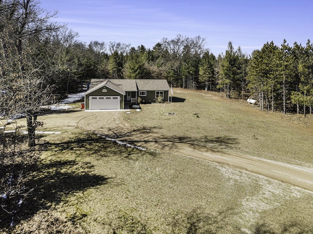 view of front of home with a forest view, an attached garage, and driveway