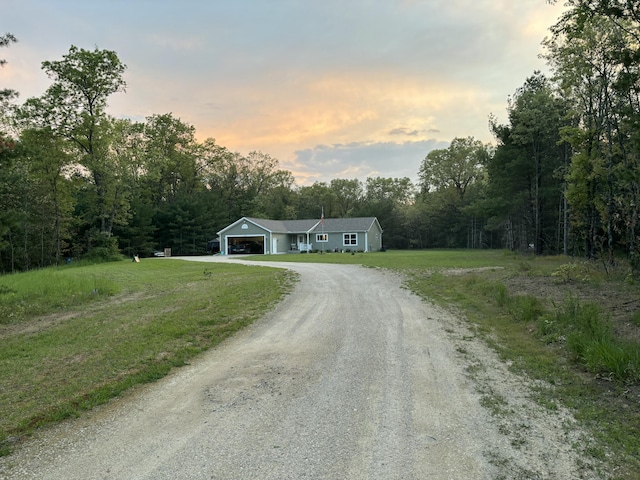 view of front of house with a wooded view, driveway, and a front yard