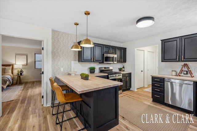 kitchen with stainless steel appliances, light wood finished floors, a breakfast bar area, and decorative backsplash