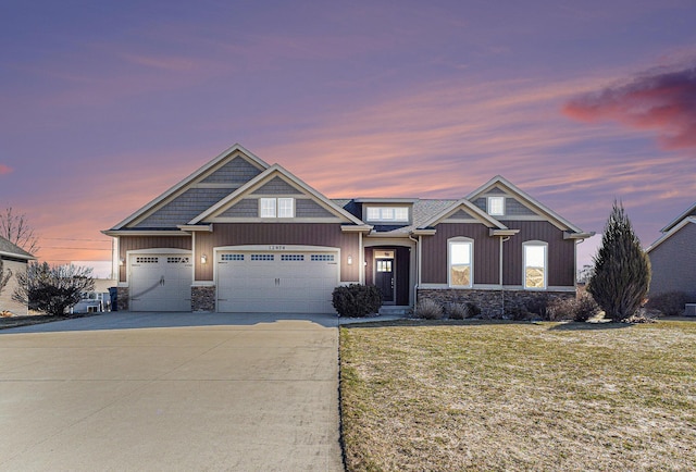 view of front of house with concrete driveway, a garage, stone siding, and a yard