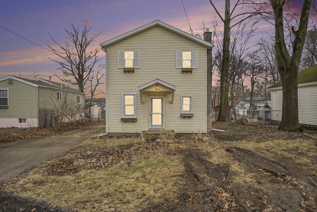 traditional home with entry steps, a chimney, and fence