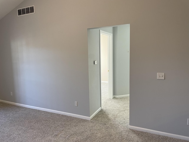 carpeted empty room featuring visible vents, baseboards, and vaulted ceiling