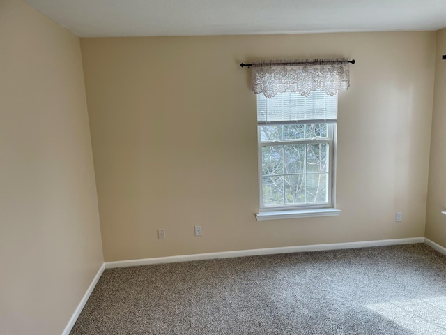 carpeted empty room featuring baseboards