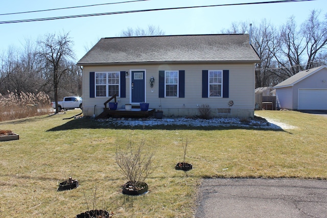 view of front facade with a shingled roof, an outbuilding, a garage, and a front lawn