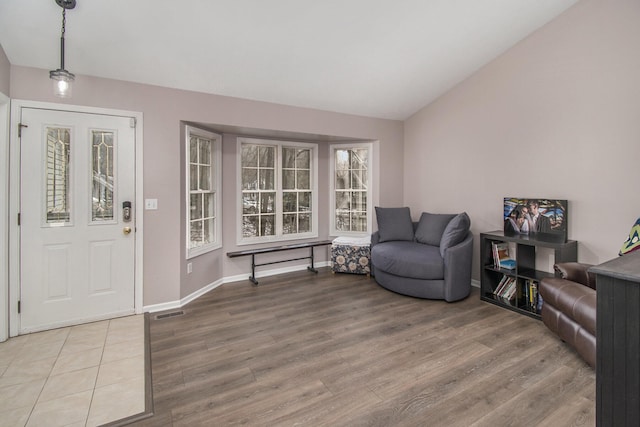 entryway with baseboards, visible vents, lofted ceiling, and light wood-style flooring