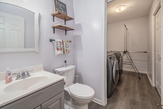 bathroom with washing machine and dryer, baseboards, toilet, wood finished floors, and vanity