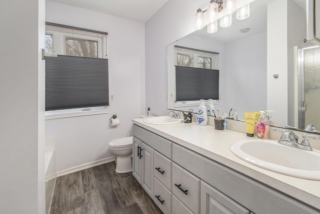 full bath with toilet, double vanity, a sink, and wood finished floors
