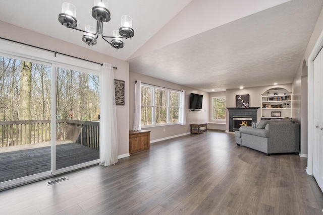living room featuring wood finished floors, visible vents, a chandelier, and a lit fireplace