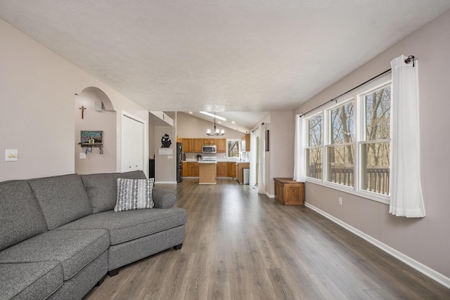 living area featuring dark wood-style floors, a notable chandelier, vaulted ceiling, baseboards, and arched walkways