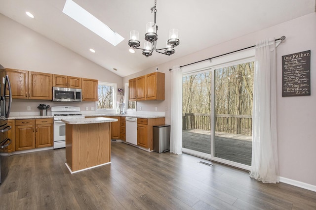 kitchen featuring visible vents, a center island, an inviting chandelier, lofted ceiling with skylight, and white appliances