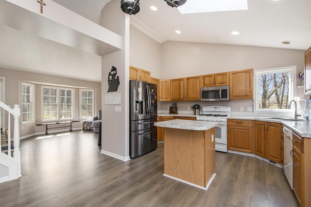 kitchen featuring dark wood finished floors, stainless steel appliances, light countertops, a sink, and a center island