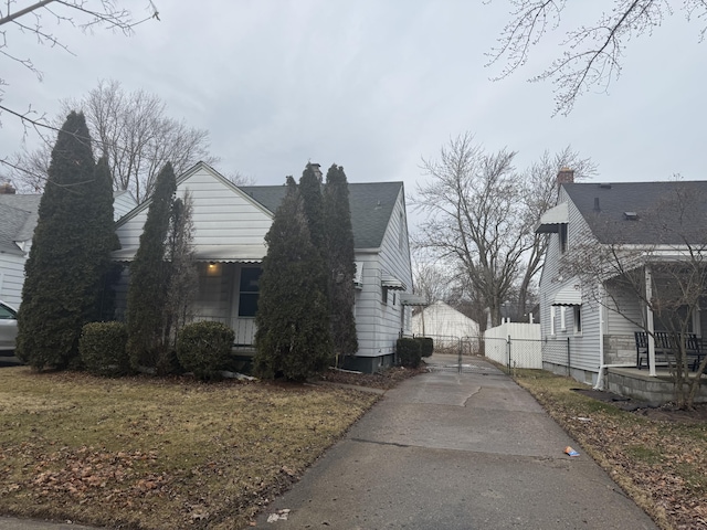 view of side of home with a gate, a chimney, fence, and roof with shingles