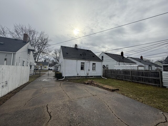 back of house with a residential view, fence, and a lawn