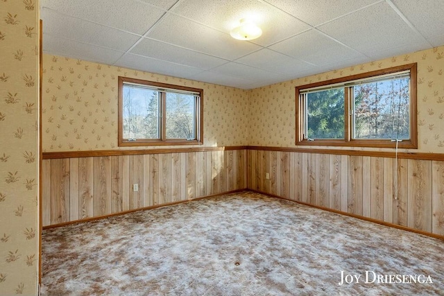 spare room with wallpapered walls, carpet flooring, a paneled ceiling, and wainscoting