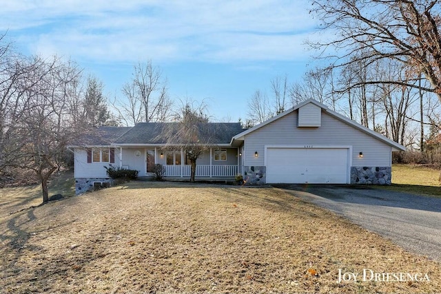 ranch-style home featuring a front lawn, a garage, covered porch, and driveway