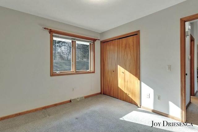 unfurnished bedroom with baseboards, visible vents, a closet, and light carpet