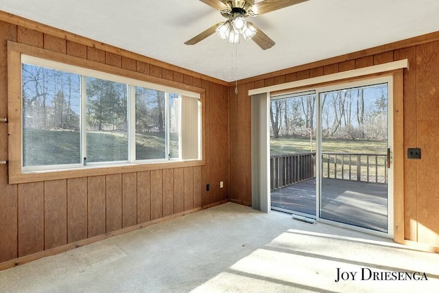 interior space featuring a wealth of natural light, wooden walls, and a ceiling fan