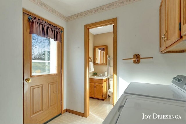 washroom featuring baseboards, light floors, cabinet space, independent washer and dryer, and a sink