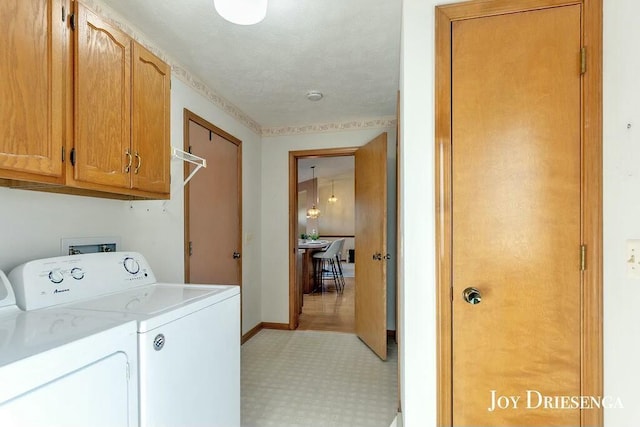 clothes washing area featuring washing machine and dryer, cabinet space, baseboards, and light floors