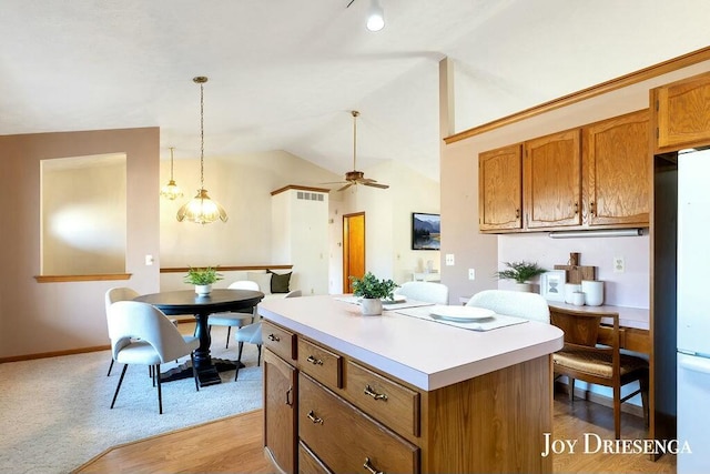 kitchen featuring visible vents, a kitchen island, light countertops, lofted ceiling, and brown cabinetry