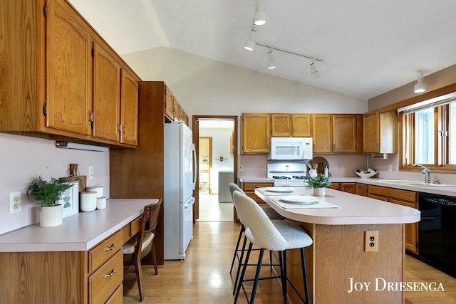 kitchen with a breakfast bar area, light countertops, lofted ceiling, white appliances, and a sink