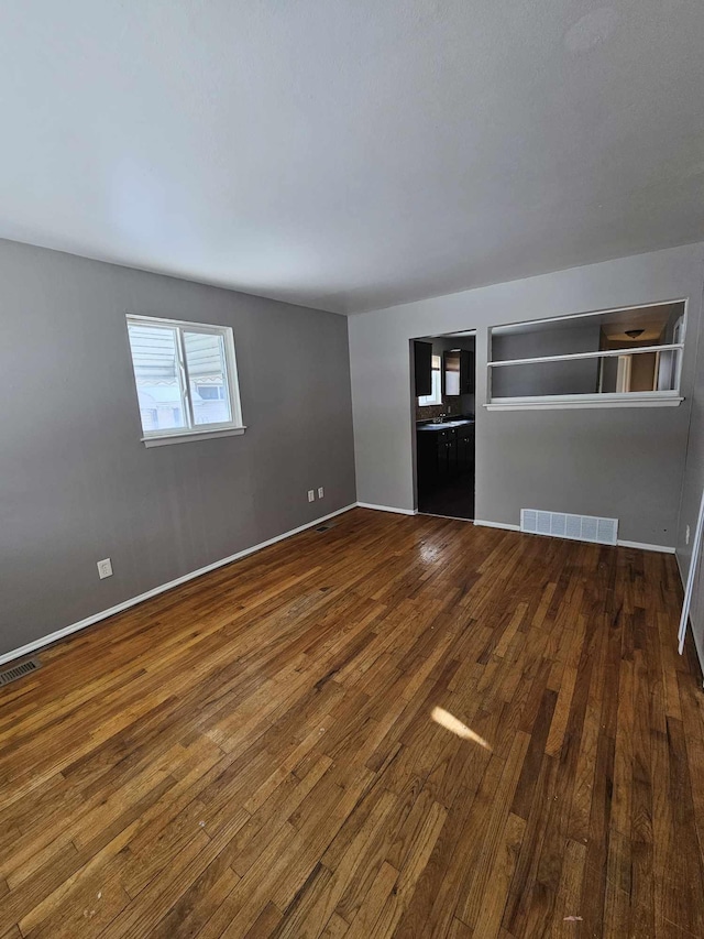 interior space featuring dark wood-style flooring, visible vents, and baseboards