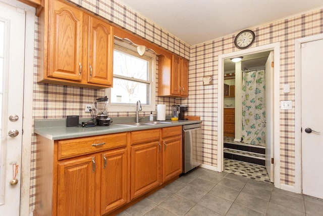 kitchen featuring a sink, dishwasher, brown cabinetry, and wallpapered walls