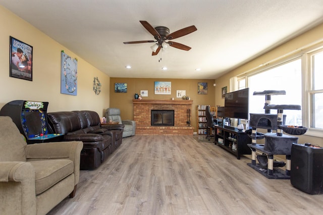 living area featuring a brick fireplace, recessed lighting, a healthy amount of sunlight, and light wood-type flooring