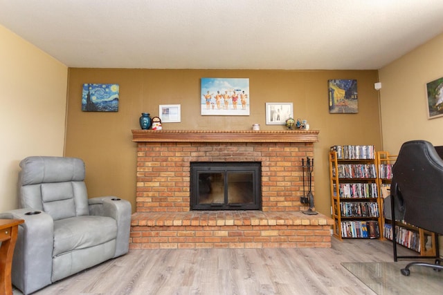 living area with a brick fireplace and wood finished floors