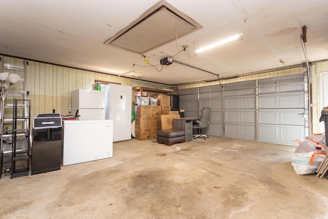 garage featuring fridge, a garage door opener, and freestanding refrigerator