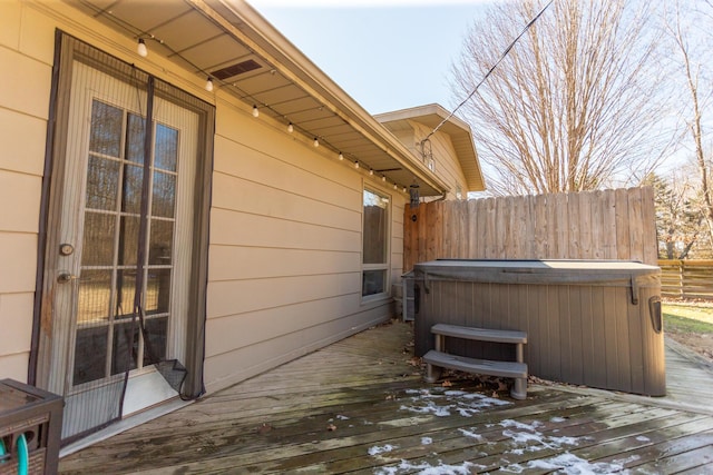 view of property exterior with a wooden deck, a hot tub, and fence