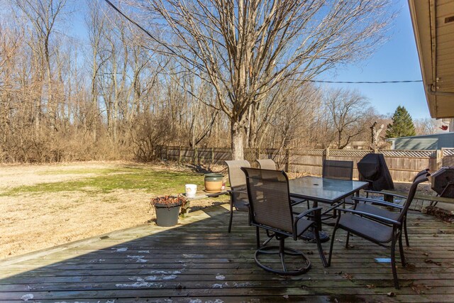 wooden terrace with outdoor dining area and a fenced backyard