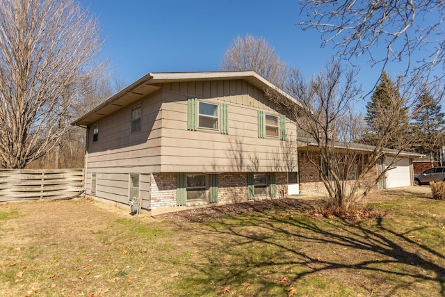 view of side of property featuring board and batten siding, a yard, fence, and a garage