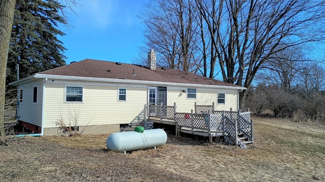 rear view of house featuring a wooden deck, a chimney, and roof with shingles