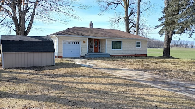 view of front of property featuring driveway, a chimney, an outdoor structure, a storage unit, and a garage