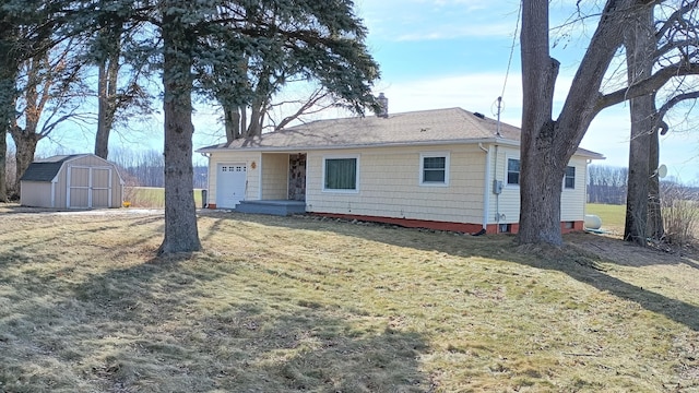 view of front of home with a front yard, a chimney, a storage shed, an outbuilding, and an attached garage